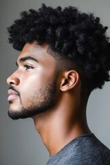 Obraz premium Captivating profile of a young man with curly hair showcasing a stylish haircut and a well-groomed beard in a minimalist setting