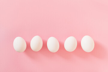 Frame of Easter white natural eggs set isolated on pastel pink background. Stylish trendy composition with chicken egg. Flat lay, top view, place for text. Happy eco-friendly holiday, minimal concept