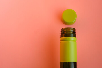 Green glass bottle with a lime green screw cap against a soft peach color background. Minimalism....