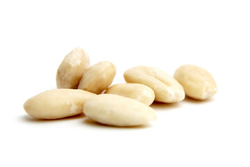 Close-up view of smooth blanched almonds scattered on a white surface. Ideal for concepts of healthy snacking, clean eating, or natural ingredients