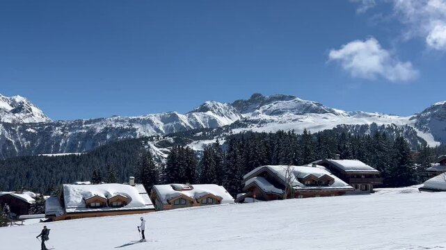 Winter scenery of a ski resort in French alps with wooden chalets on the slope
