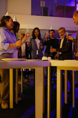 A group of seven employees stand and hold glasses, in a hall, at a retirement party