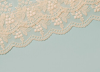 Delicate vintage ivory lace on pale blue background, creative old fashioned layout.
