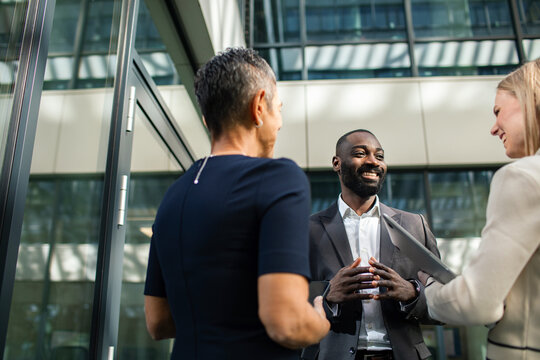 Diverse business professionals having a conversation outside modern office building