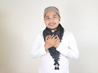 Handsome Asian Muslim man wearing a black turban or shemagh shows a gesture conveys honor, faith,...