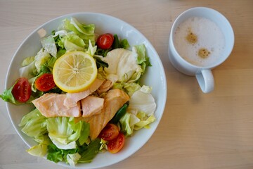 White plate of fresh salad with boiled red fish, greens, and tomatoes showcasing healthy eating and gourmet cuisine concept of nutrition, culinary arts, food styling