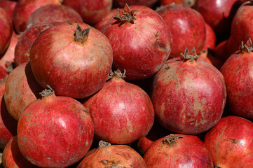Vibrant pomegranates stacked together in a sunlit market display