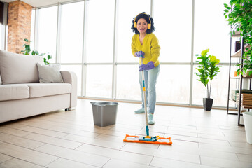 Young woman cleaning living room with a mop, wearing casual clothes, daytime, indoor apartment...