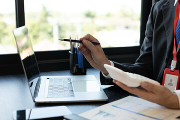 Naklejka premium A man in a suit is working on documents in an office. He holds a pen and is analyzing data. This scene conveys a professional working atmosphere. 