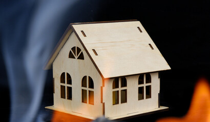 Fire flame, smoke and wooden house model on black background.	