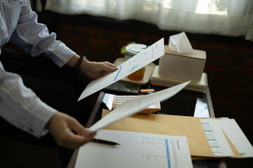 the businessman is sitting at a desk with a calculator and a stack of papers. She is looking at the...