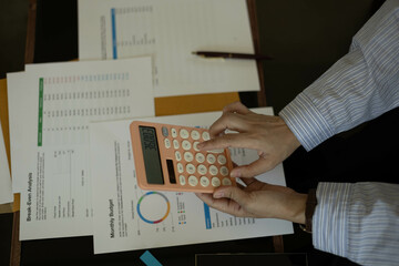 the businessman is sitting at a desk with a calculator and a stack of papers. She is looking at the...