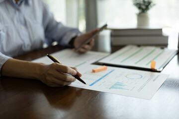 the businessman is sitting at a desk with a calculator and a stack of papers. She is looking at the papers and seems to be deep in thought
