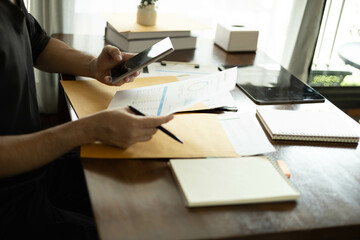 Fototapeta premium the businessman is sitting at a desk with a calculator and a stack of papers. She is looking at the papers and seems to be deep in thought 
