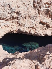 Mysterious Cave Opening with Deep Blue Water Surrounded by Rocky Cliffs