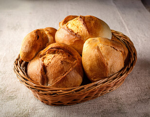 A traditional Portuguese bread basket filled with broa de milho loaves placed on a linen tablecloth