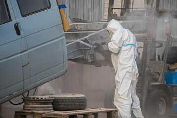 industrial processing of rusty metal of a car body with a sandblasting machine