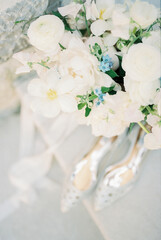 Wedding bouquet stands on the table near bride shoes. Top view