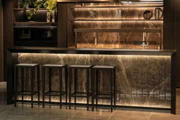 Luxurious dark kitchen with island, bar seating, marble finishes and built-in appliances