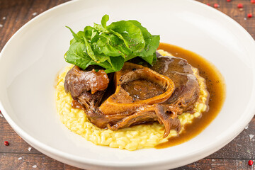Gourmet osso buco with saffron risotto and fresh greens on a plate