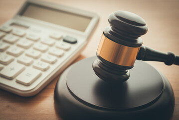 Gavel hammer judge and white calculator on wooden table background. Tax law, financial law or...