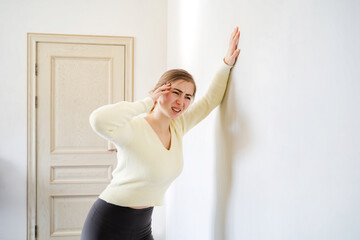 A young woman suffering from dizziness leaning against the wall for support. Girl feeling dizzy...