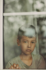 portrait of a boy looking out window