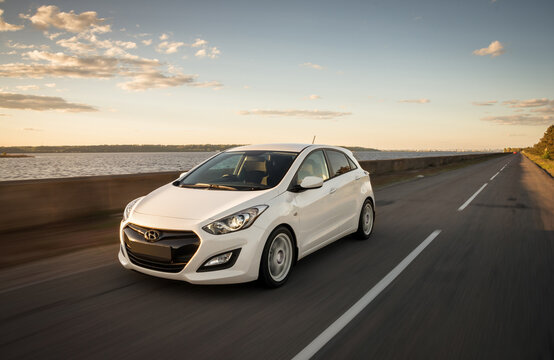 White Hyundai i30 driving along huge lake. Motion shot of korean compact hatchback in rural setting. Kyiv region, Ukraine - May 06 2014.