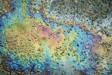 Oil Slick Creates Vibrant Patterns on Wet Asphalt Surface During a Rainy Day