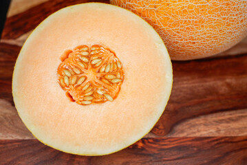 Fresh cantaloupe melon cut in half on a wooden surface