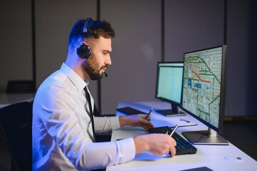 Center of dispatching maintenance. Portrait of man working via headset microphone while sitting on...