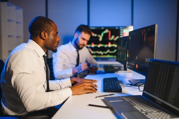 Obraz premium Conception of teamwork. Team of stockbrokers works in modern office with many display screens