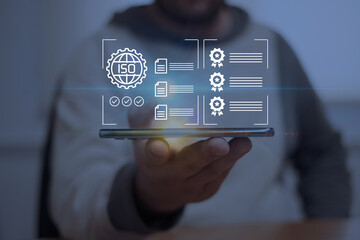 Digital certification and ISO standard compliance concept. Businessman using mobile technology for quality assurance, online document verification, and professional accreditation.