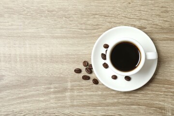 Cup of coffee with coffee beans on wooden background
