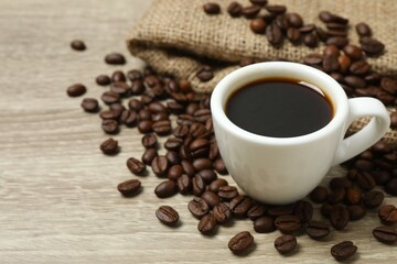 Fototapeta premium Cup of coffee with coffee beans on wooden background