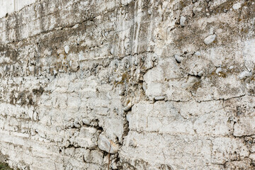 Cement wall with pebbles, whitewash paint, layers, earth reinforcement, full-frame background.