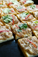 Minced pork toast prepared on black tray for deep-fried cooking. Close-up minced porn toast or Thai pork toast for Thai recipes, home cooking preparation, deep-fried food, vegetable, and Asia cuisine.