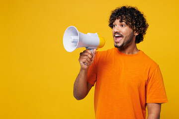 Young happy Indian man he wearing orange t-shirt casual clothes hold in hand megaphone scream...
