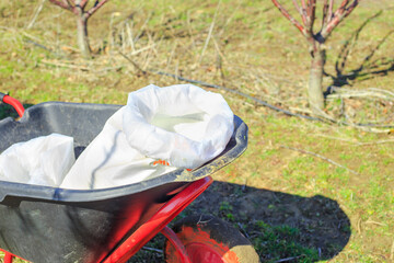 Garden wheelbarrow with a bag of mineral granulated fertilizers for feeding trees in an orchard in...