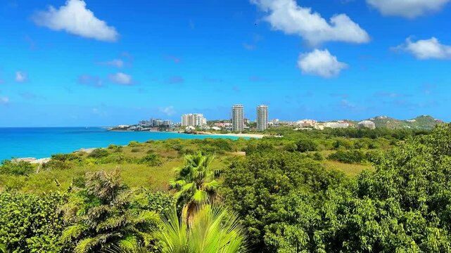 Beautiful panoramic view of the Caribbean island of Saint Martin (Sint Maarten), showcasing its crystal-clear turquoise waters, white sandy beaches, lush green hills, and vibrant coastal scenery