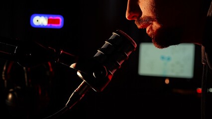 Radio Host Speaking into Microphone in a Dark Studio