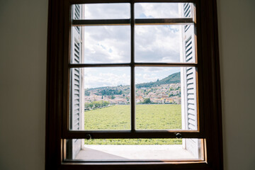 Fototapeta premium View from the window of green vineyards and a settlement at the foot of the mountains