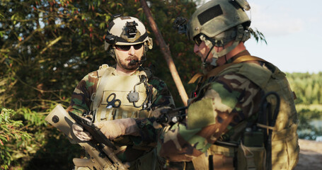 Soldiers in camouflage uniforms with rifles over their shoulders and helmets on their heads check...