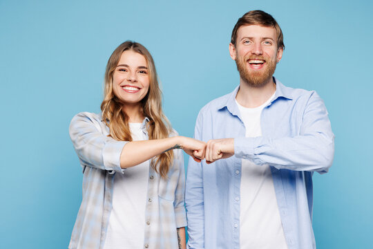 Young smiling couple two friends family man woman wear shirt casual clothes together do fist bump gesture look camera isolated on pastel plain light blue background studio portrait. Lifestyle concept.