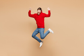 Full body young man wear red hoodie casual clothes jump high doing winner gesture celebrate...