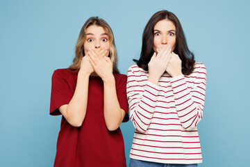Young shocked surprised couple two friends women wear red casual clothes together cover mouth with hands look camera isolated on pastel plain light blue background studio portrait. Lifestyle concept.