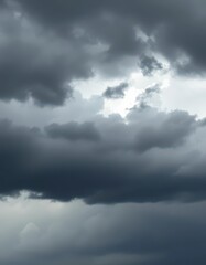 Obraz premium Ominous, brooding storm clouds; dark grey, charcoal, silver linings, heavy rain, atmospheric, moody, dramatic sky, dramatic sky, light and shadow