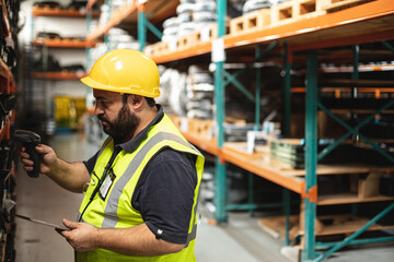 Worker in safety gear scanning inventory in busy hydraulics factory warehouse