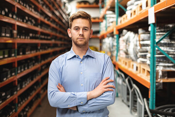 Confident man standing in warehouse surrounded by hydraulic equipment and shelves