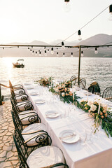 Set festive table with bouquets of flowers stands on a pier by the sea